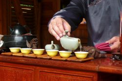 Chinesische Teezeremonie: Ein Mann schenkt Tee in mehrere Tassen ein - das ist für einen Edel-tee fast ein Muss.